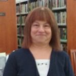 Image of Ann Stolinsky, smiling in a library.